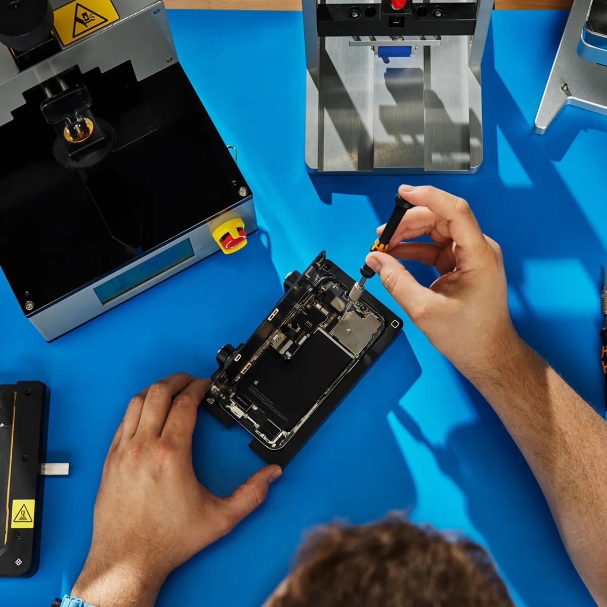 Técnico da iTelas consertando um iPhone na bancada, em Curitiba